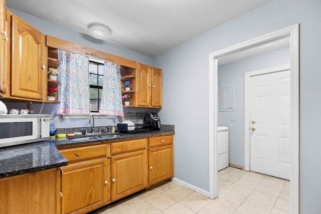 kitchen with a sink, light tile patterned flooring, open shelves, washer / dryer, and white microwave