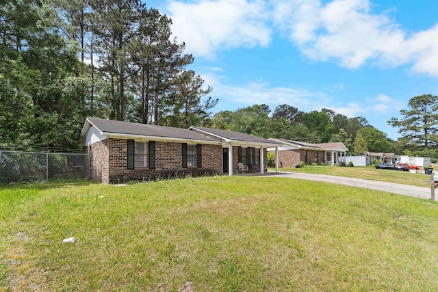 ranch-style home with a front yard, driveway, brick siding, and fence