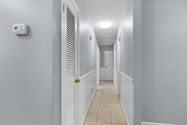 hall featuring light tile patterned floors and attic access