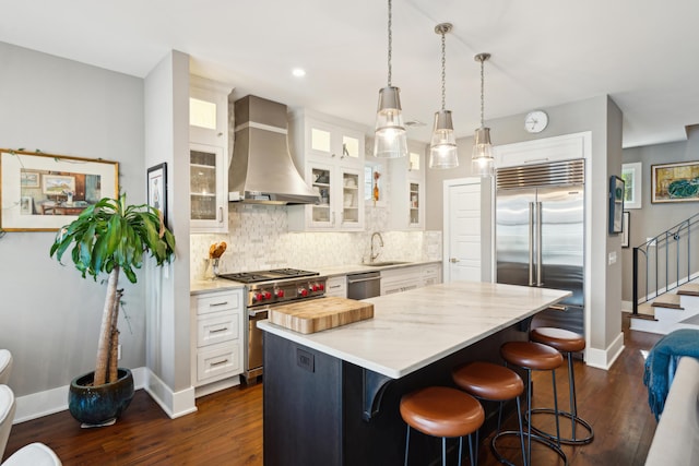 kitchen featuring white cabinets, a center island, wall chimney exhaust hood, and high quality appliances