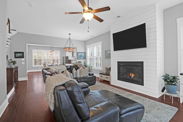 living room featuring a large fireplace, ceiling fan, and dark hardwood / wood-style floors