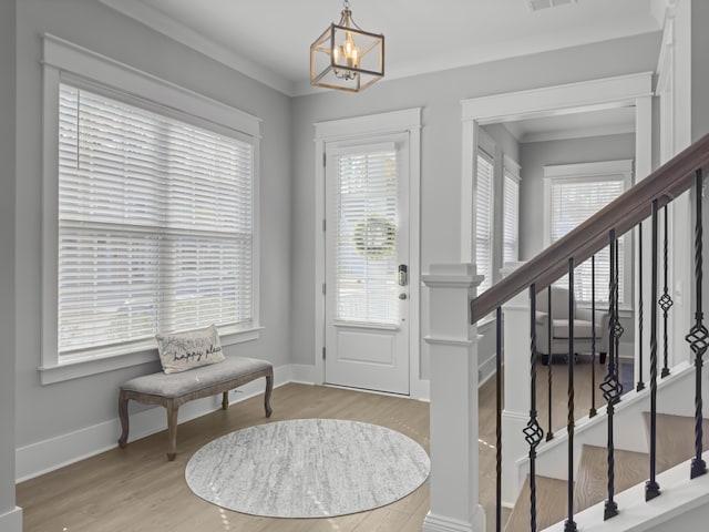 entrance foyer featuring light wood-style floors, plenty of natural light, stairs, and ornamental molding