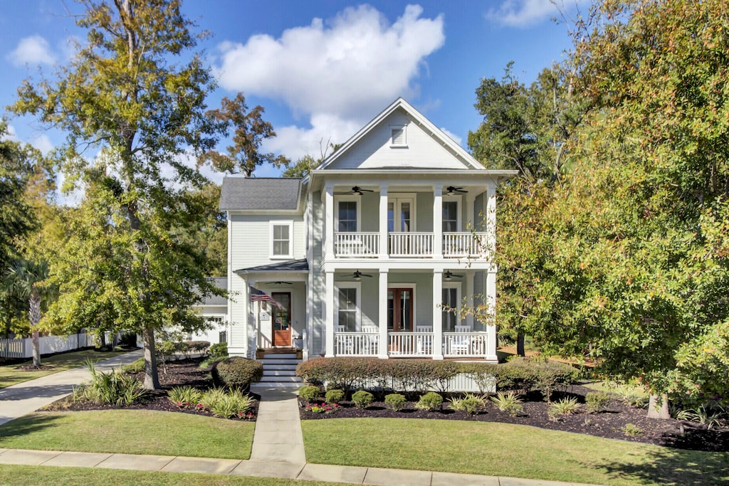 neoclassical home with covered porch, a front yard, and ceiling fan