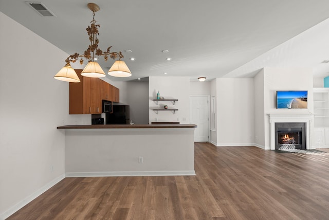 kitchen featuring kitchen peninsula, hardwood / wood-style floors, hanging light fixtures, and black appliances