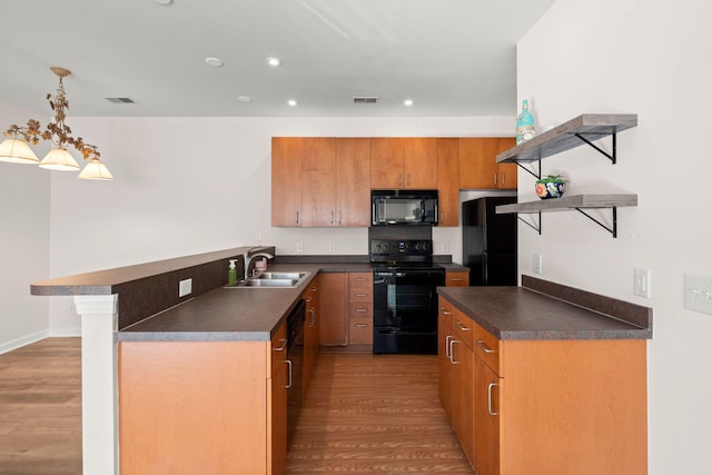 kitchen with pendant lighting, a breakfast bar, black appliances, sink, and light hardwood / wood-style flooring