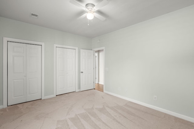 unfurnished bedroom with light carpet, ceiling fan, and multiple closets