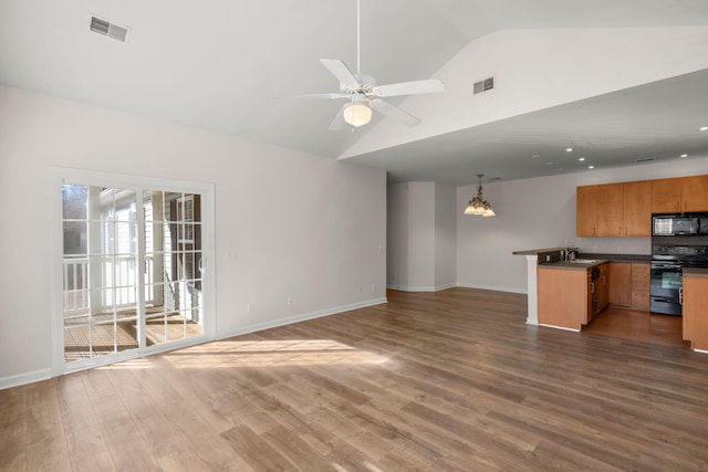 unfurnished living room featuring ceiling fan with notable chandelier, dark hardwood / wood-style flooring, sink, and vaulted ceiling