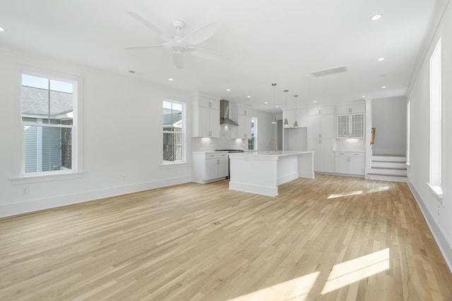 unfurnished living room with light wood-type flooring, ceiling fan, crown molding, and sink