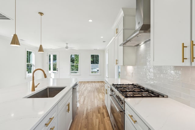 kitchen featuring sink, white cabinets, stainless steel appliances, and wall chimney range hood