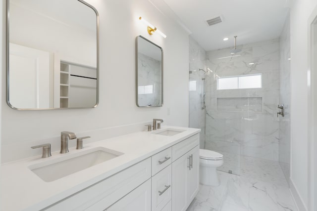 bathroom featuring toilet, a tile shower, and vanity