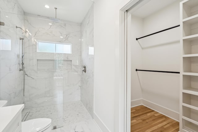 bathroom with a tile shower, hardwood / wood-style floors, and toilet