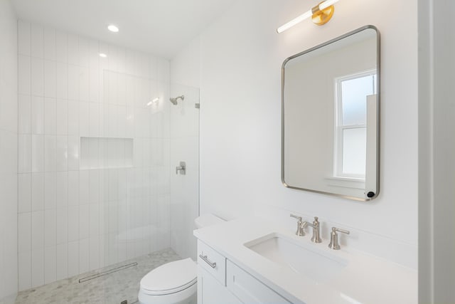 bathroom featuring tiled shower, vanity, and toilet