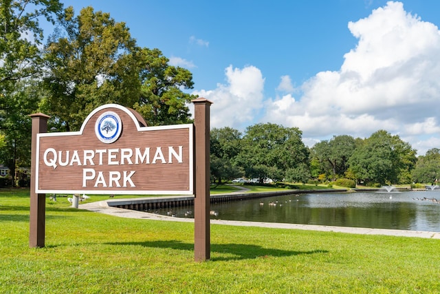 community / neighborhood sign with a yard and a water view