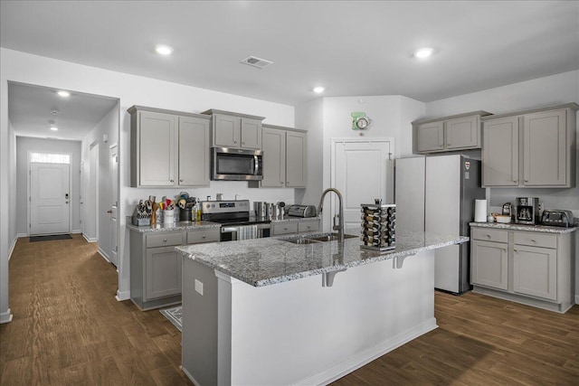 kitchen with a kitchen island with sink, sink, gray cabinets, appliances with stainless steel finishes, and dark hardwood / wood-style flooring