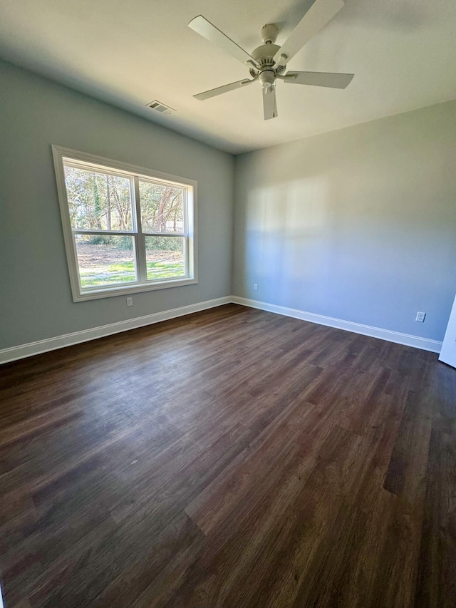 unfurnished room with dark wood-type flooring, a ceiling fan, visible vents, and baseboards