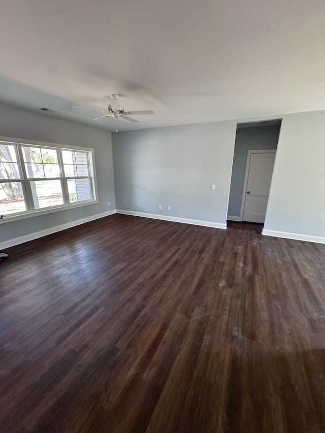 empty room featuring dark wood-style floors, baseboards, and a ceiling fan