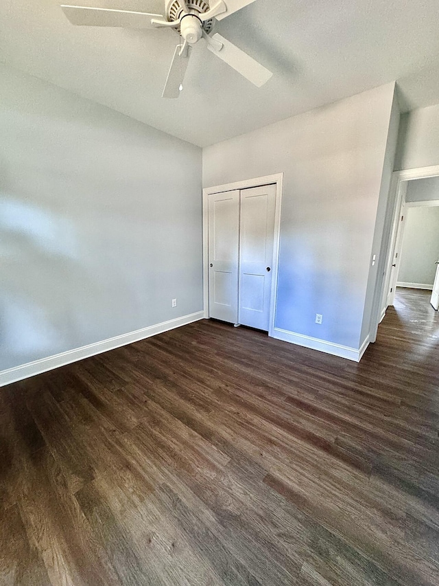 unfurnished bedroom with dark wood-style floors, a closet, and baseboards