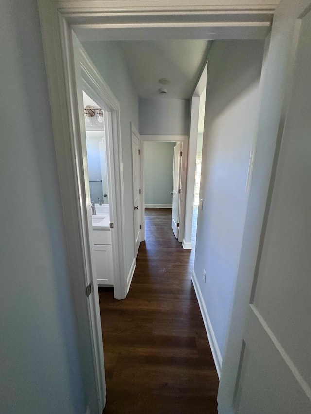 hall featuring dark wood-type flooring and baseboards