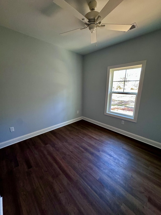 spare room featuring baseboards, dark wood finished floors, and a ceiling fan