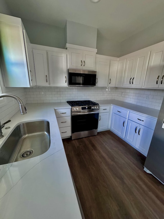 kitchen featuring decorative backsplash, appliances with stainless steel finishes, white cabinets, and a sink