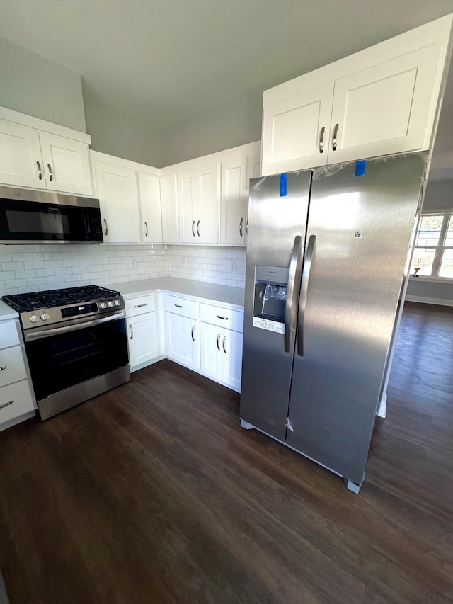 kitchen with tasteful backsplash, white cabinets, dark wood-type flooring, stainless steel appliances, and light countertops