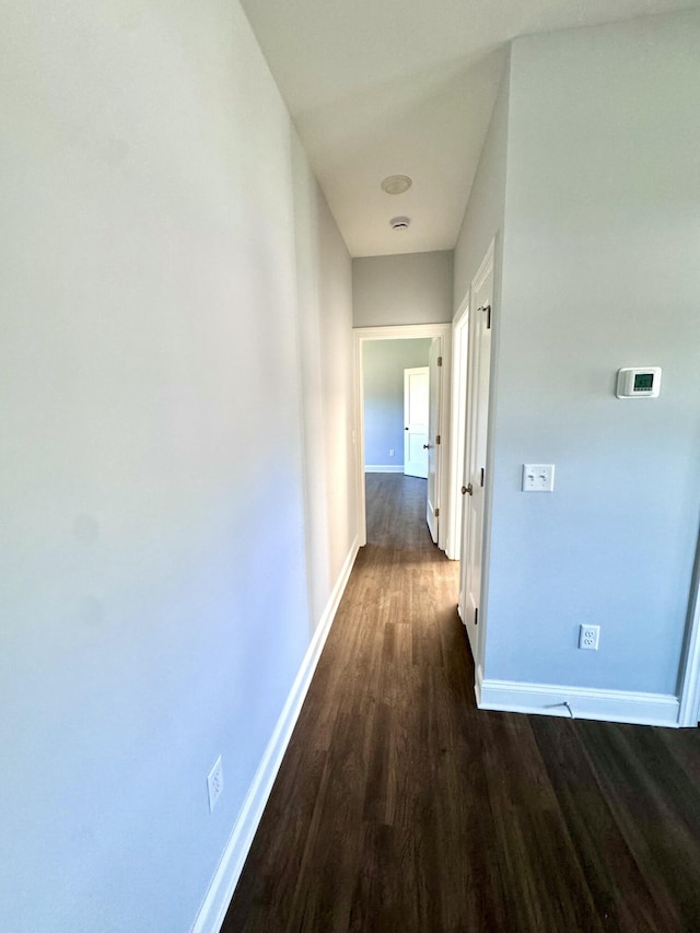 hallway with dark wood-type flooring and baseboards