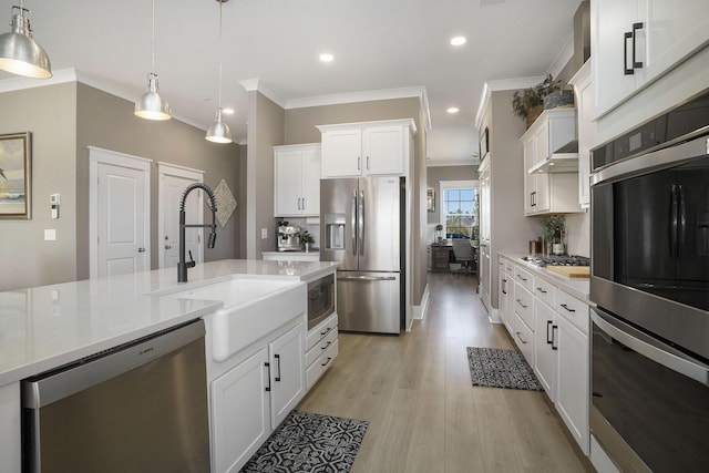 kitchen with a sink, appliances with stainless steel finishes, light wood-style flooring, and light countertops