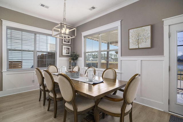 dining room with visible vents, an inviting chandelier, light wood-style flooring, and crown molding