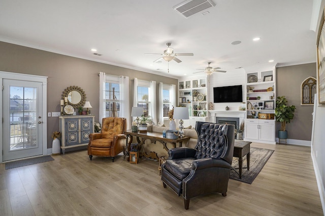 living area with a ceiling fan, visible vents, a wealth of natural light, and light wood-type flooring