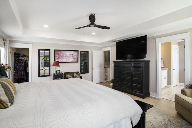 bedroom featuring a spacious closet, recessed lighting, a raised ceiling, and light wood-style floors