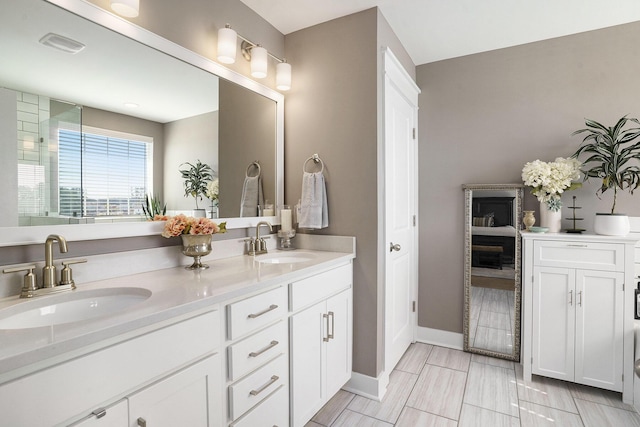 bathroom featuring double vanity, baseboards, visible vents, and a sink