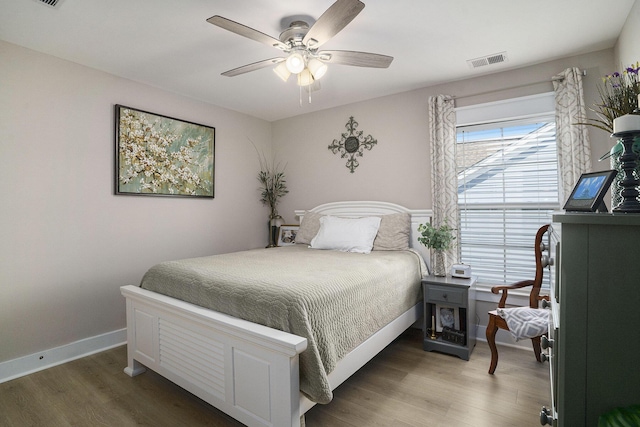 bedroom with visible vents, baseboards, wood finished floors, and a ceiling fan