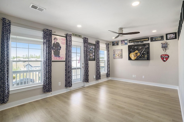 spare room with a ceiling fan, wood finished floors, visible vents, and a wealth of natural light