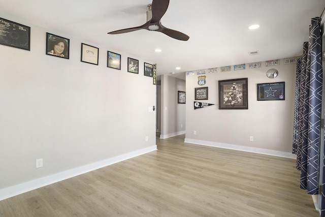 spare room featuring light wood finished floors, baseboards, and ceiling fan