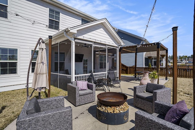 view of patio featuring an outdoor living space with a fire pit, fence, a pergola, and a sunroom