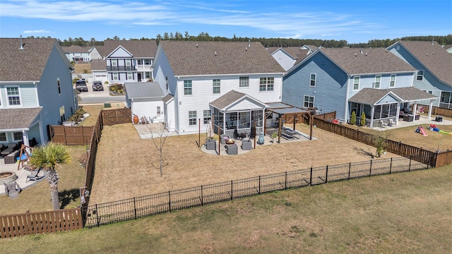 rear view of house featuring a gate, a patio, a fenced backyard, a residential view, and a sunroom