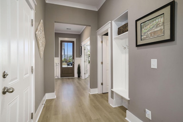 hallway featuring baseboards, light wood-style flooring, and crown molding