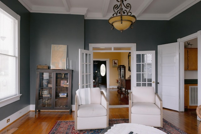 sitting room with ornamental molding, a high ceiling, hardwood / wood-style floors, and visible vents