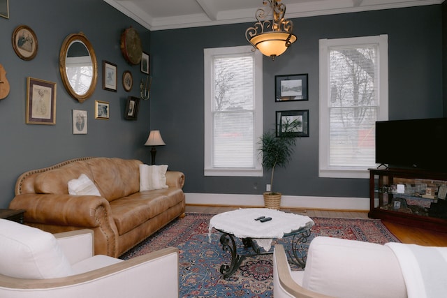 living area with baseboards, wood finished floors, beam ceiling, and crown molding