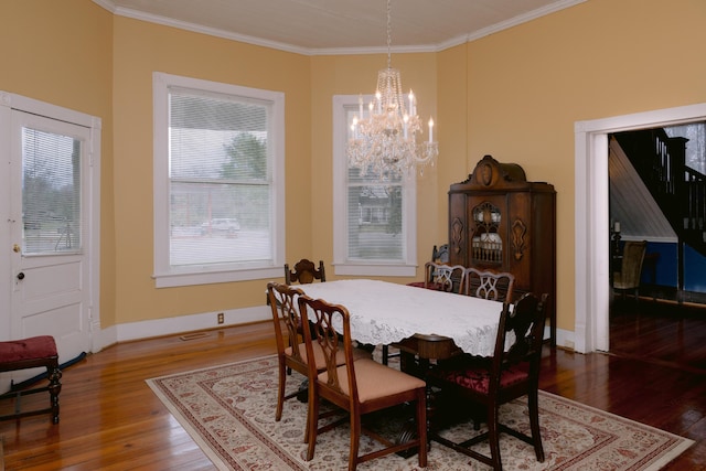dining space with wood finished floors, crown molding, a notable chandelier, and baseboards