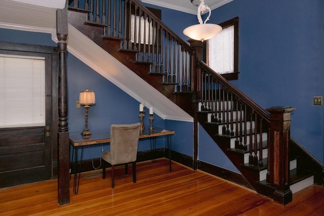 stairs featuring wood finished floors, crown molding, and baseboards
