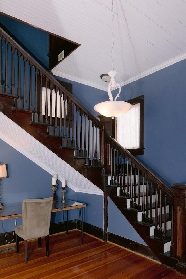 stairs with ornamental molding and wood finished floors