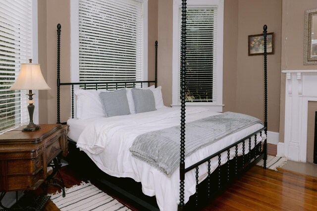bedroom with wood finished floors, baseboards, and multiple windows