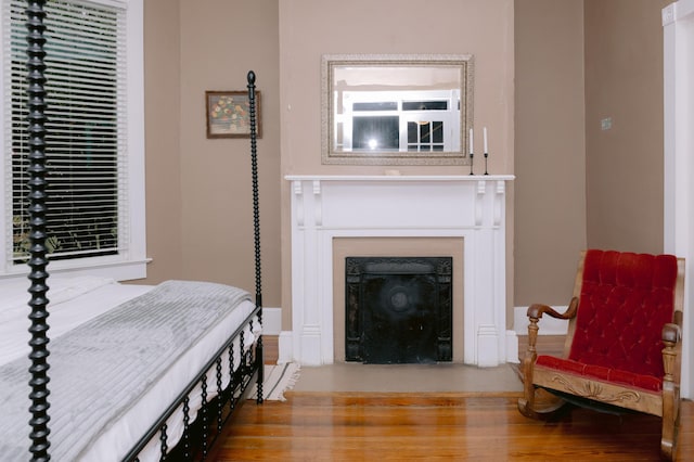 sitting room featuring a fireplace with flush hearth, wood finished floors, and baseboards