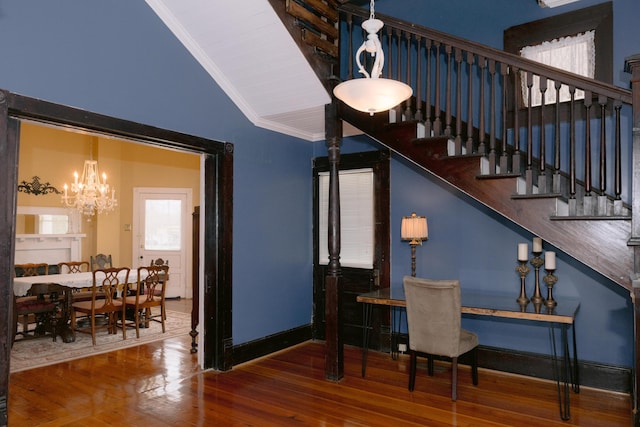 interior space with wood finished floors, an inviting chandelier, stairs, baseboards, and lofted ceiling