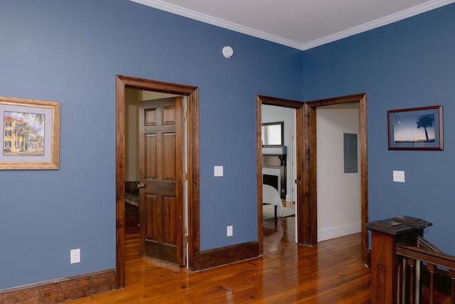 interior space featuring baseboards, electric panel, crown molding, and wood-type flooring