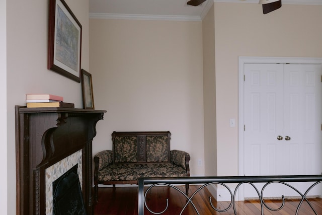 sitting room with a fireplace, wood finished floors, and crown molding