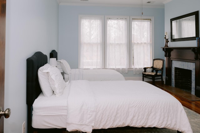 bedroom with ornamental molding, wood finished floors, and a fireplace
