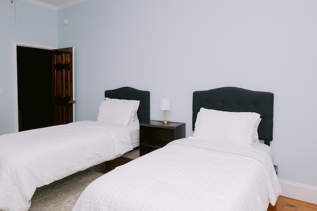 bedroom featuring ornamental molding, wood finished floors, and baseboards