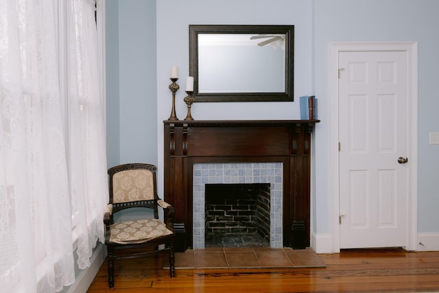 sitting room with a tiled fireplace and wood finished floors